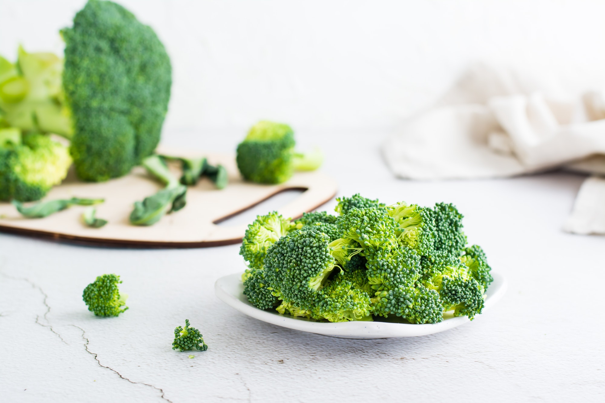 Pieces of raw broccoli on a plate on a light table.